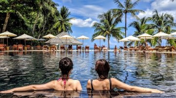 two woman leaning on inground pool tile